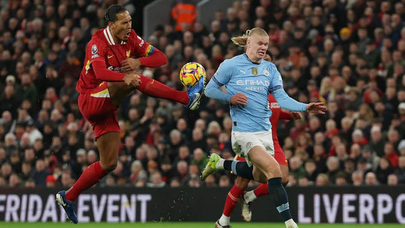 Bek tengah sekaligus kapten Liverpool, Virgil van Dijk (kiri) menahan laju bola dan pergerakkan dari striker Man City, Erling Haaland.
